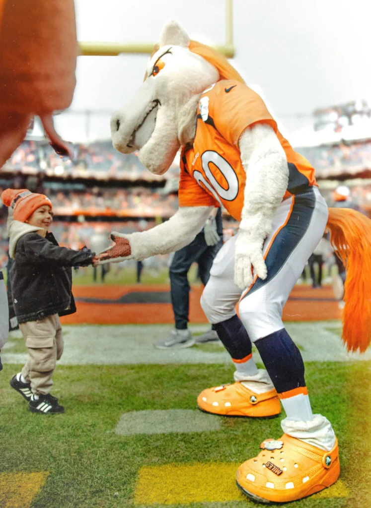 Denver Broncos mascot clapping the hand of a young fan.